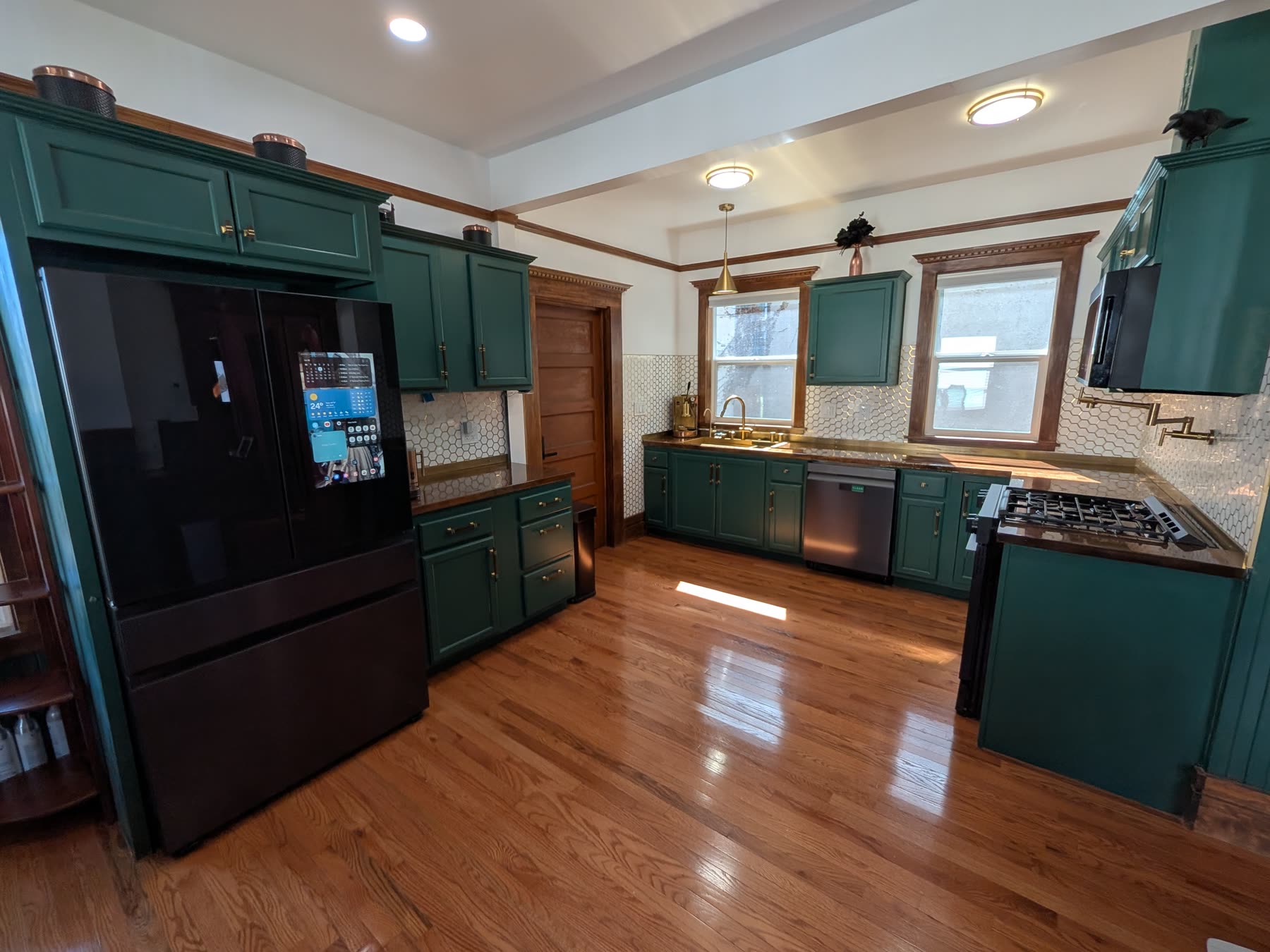 Forest-green kitchen with smart appliances and hardwood floors